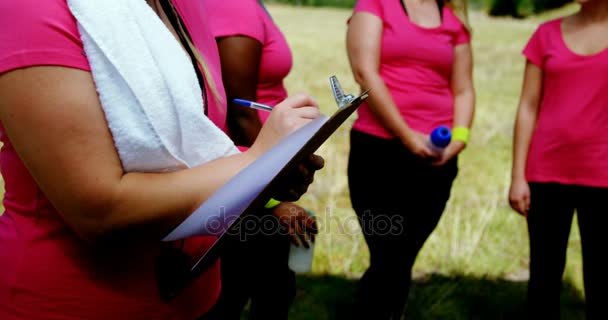Treinador feminino escrevendo na área de transferência no campo de treinamento — Vídeo de Stock