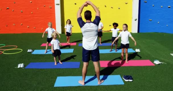Yoga-instructeur instrueren van kinderen bij het uitvoeren van de oefening — Stockvideo