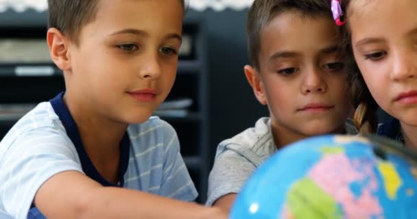 Шкільні діти обговорюють на земній кулі в класі — стокове відео