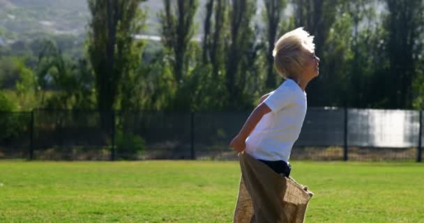 Niños jugando una carrera de sacos en el parque — Vídeo de stock