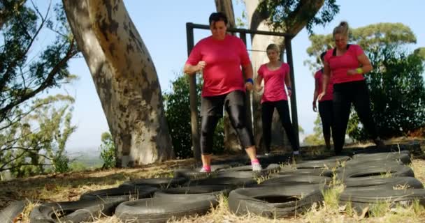 Mulheres que atropelam pneus durante o percurso de obstáculos — Vídeo de Stock