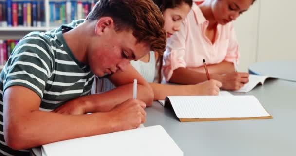 Niños de la escuela haciendo deberes en la biblioteca — Vídeo de stock