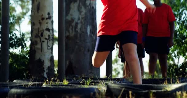 Παιδιά που τρέχουν πάνω από ελαστικά κατά τη διάρκεια της κατάρτισης σειράς μαθημάτων εμποδίων — Αρχείο Βίντεο