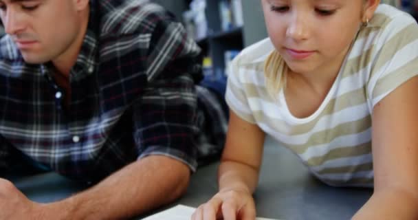 Studentessa sdraiata sul pavimento e libro di lettura in classe — Video Stock