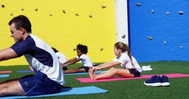 Инструктор по йоге инструктирует детей выполнять упражнения — стоковое видео