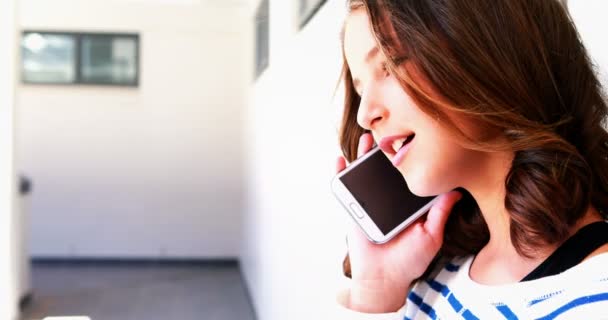 Школярка розмовляє по мобільному телефону в коридорі — стокове відео