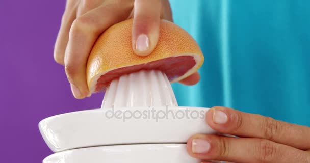 Mujer preparando jugo de naranja de sangre de exprimidor sobre fondo violeta — Vídeos de Stock