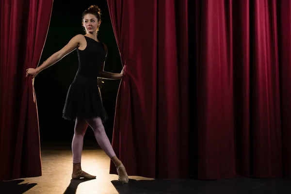 Balerina, pózol, piros színpadi függöny előtt — Stock Fotó