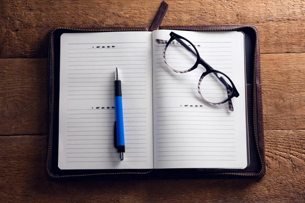 Spectacles and pen on organizer at desk — Stock Photo, Image