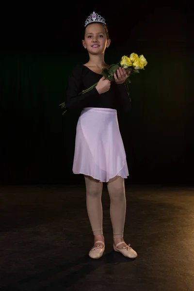 Ballerina posing with flower bouquet on stage — Stock Photo, Image