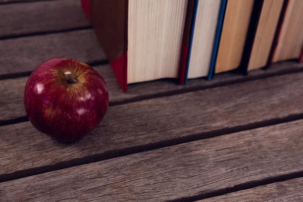 Apple e livros dispostos em mesa de madeira — Fotografia de Stock