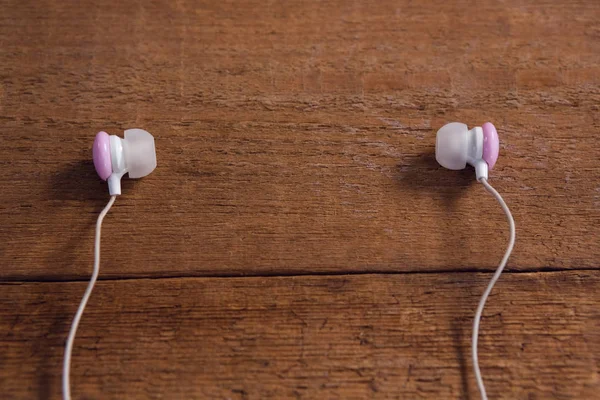 Pink earphones on wooden table — Stock Photo, Image