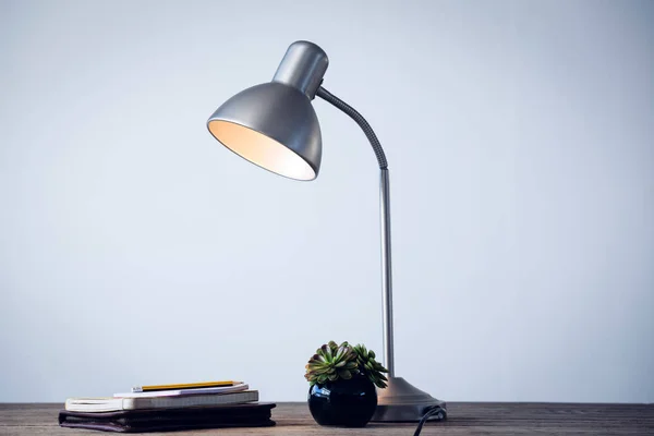 Lampa na biurko oświetlony przez książek na stole — Zdjęcie stockowe