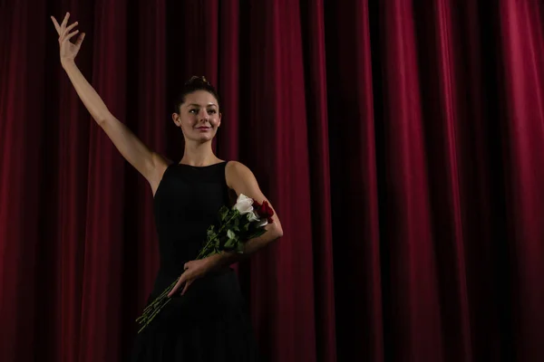 Ballerina posiert mit Blumenstrauß auf der Bühne — Stockfoto