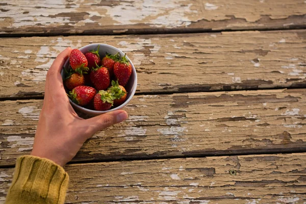 Hand of woman holding bowl containing strawberries — Stock Photo, Image