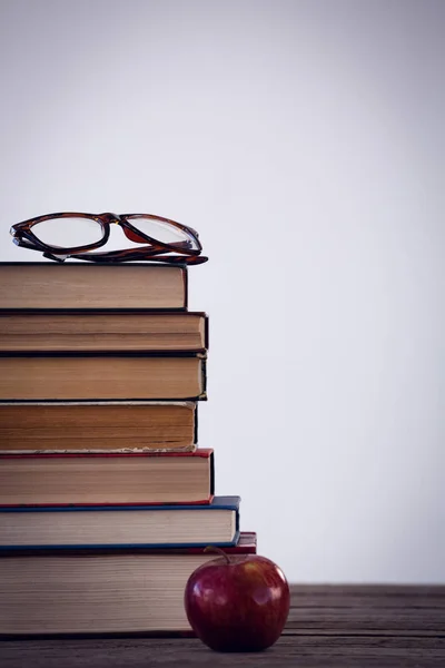 Manzana por libros con gafas en la mesa — Foto de Stock