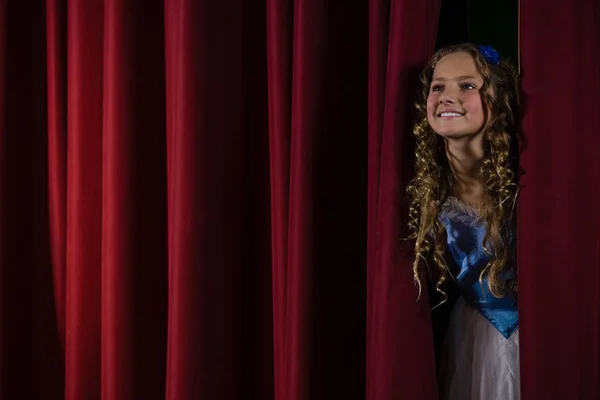 Female artist peeking through the red curtain — Stock Photo, Image