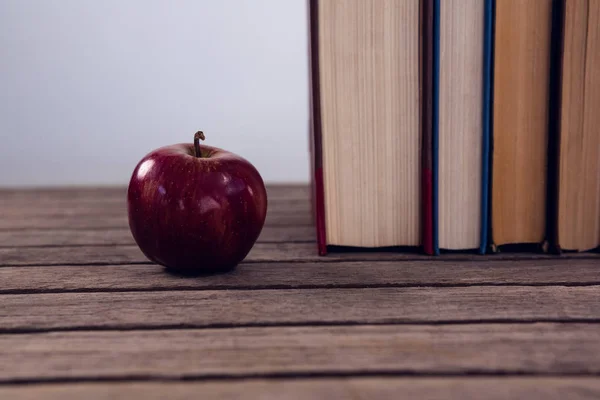 Manzana y libros dispuestos en mesa de madera —  Fotos de Stock