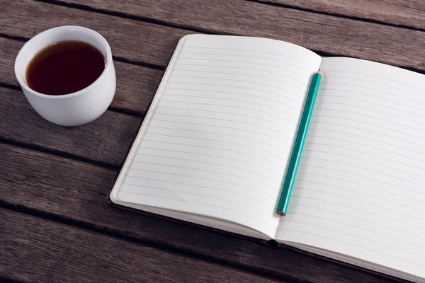Bleistift auf geöffnetem Tagebuch mit Tasse schwarzen Kaffee — Stockfoto