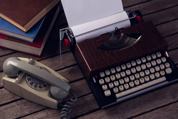 Винтажная пишущая машинка и телефон на деревянном столе — стоковое фото
