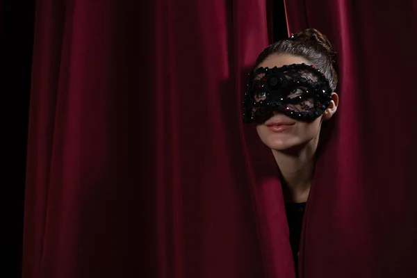 Female artist in mask peeking through curtain — Stock Photo, Image