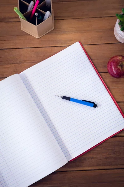 Kirja kynällä ja omena huonekasvi — kuvapankkivalokuva