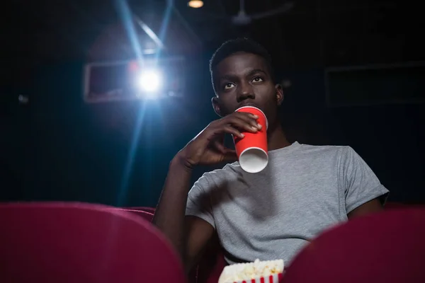 映画を見ながら冷たい飲み物を飲む男性 — ストック写真