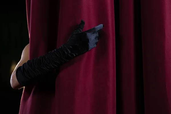 Mão em uma luva preta puxando cortina de distância — Fotografia de Stock