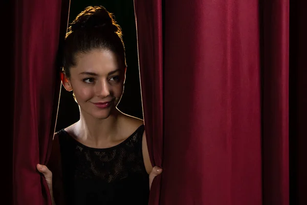 Ballet dancer peeking through a stage curtain — Stock Photo, Image