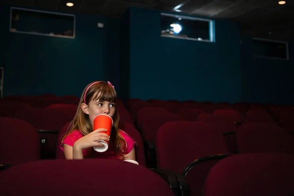 Дівчина п'є на сидінні в кінотеатрі — стокове фото