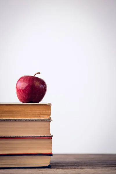 El primer plano de la manzana en los libros a la mesa —  Fotos de Stock