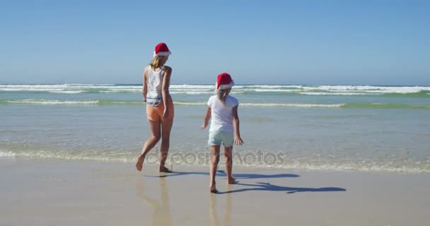 Mutter und Tochter spazieren an einem sonnigen Tag am Strand — Stockvideo