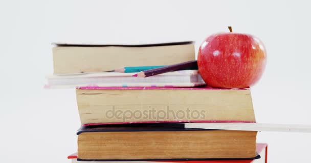 Libros, Lápices de color y manzana sobre fondo blanco — Vídeos de Stock