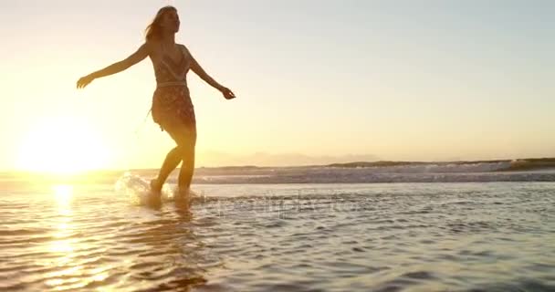 Donna con le braccia tese che gioca in acqua in spiaggia — Video Stock