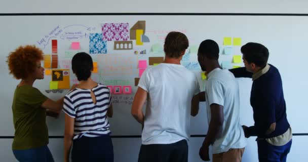 Team of executives discussing over sticky notes on whiteboard — Stock Video