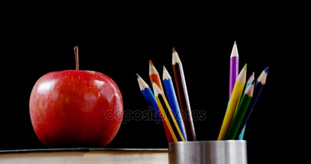Maçã no livro com lápis de cor na mesa — Vídeo de Stock