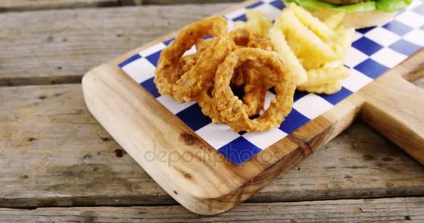 Hamburguesa, anillo de cebolla y papas fritas en la tabla de picar — Vídeos de Stock