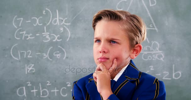 Thoughtful schoolboy standing in front of chalkboard — Stock Video