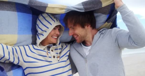 Casal feliz escondido em cobertor na praia — Vídeo de Stock