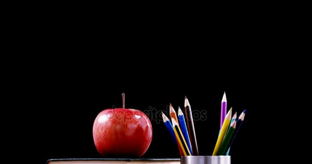 Apple on book stack with color pencil on table — Stock Video