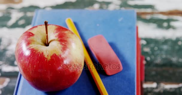 Яблуко, олівець і гумка на книжковому стеку — стокове відео