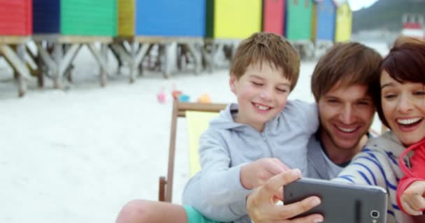 Lycklig familj med mobiltelefon på stranden — Stockvideo