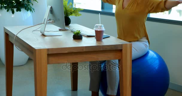 Kvinnliga verkställande gör övning på övning boll på hennes skrivbord — Stockvideo