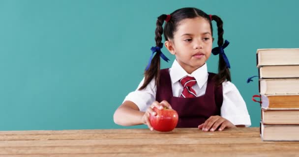 Schoolmeisje houden van apple op stapel boeken — Stockvideo