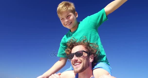 Pai carregando filho em seus ombros na praia — Vídeo de Stock