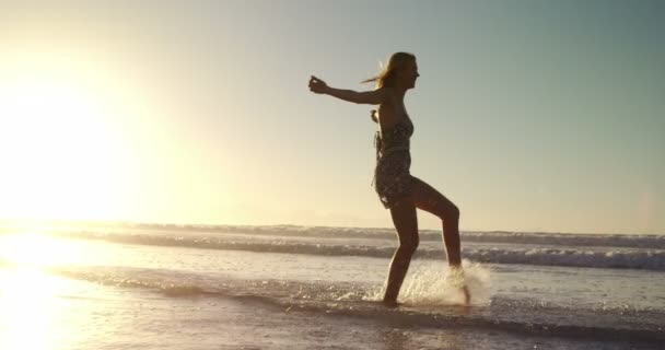 Femme avec les bras tendus jouant dans l'eau à la plage — Video