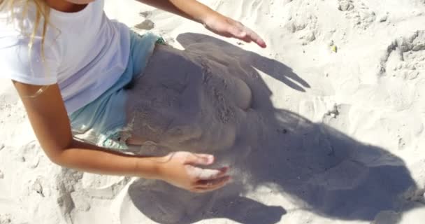 Meisje spelen met zand op strand — Stockvideo