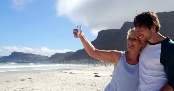 Moeder en zoon selfie vanaf mobiele telefoon nemen op strand — Stockvideo