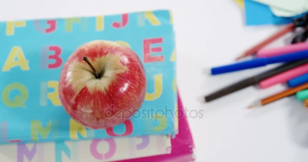 Manzana en la pila de libros con varios artículos de papelería — Vídeos de Stock