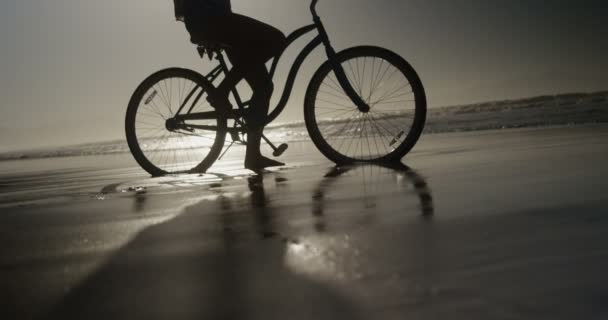 Silhouet van de vrouw zitten met armen gestrekt op fiets — Stockvideo